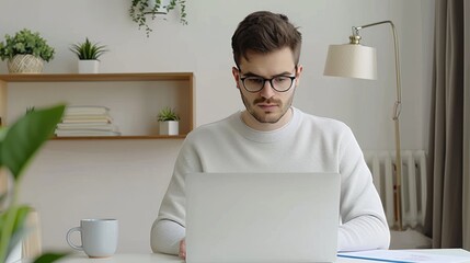 Poster - A man sits at a table in his home office, working on a laptop computer