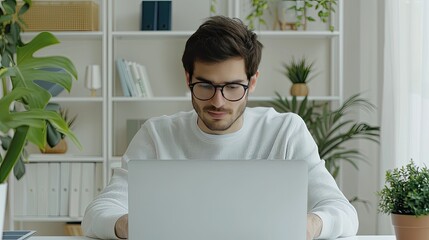 Poster - A man sits at a table in his home office, working on a laptop computer