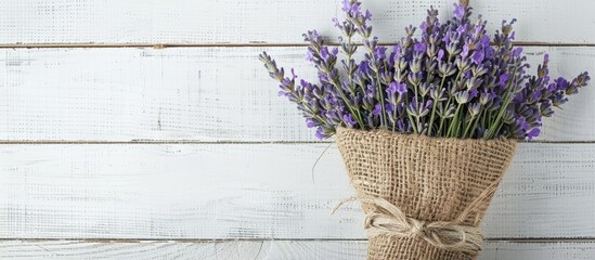 Poster - A dried lavender bouquet, gift-wrapped in textured green burlap, set on a white wooden background. Ideal for aromatherapy, organic home decor, spa, and Mother's Day, with room for copy space image.