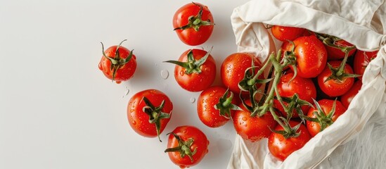 Poster - Overhead view of fresh tomatoes next to an eco-friendly bag on a white background with copy space image.