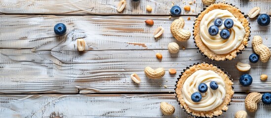 Poster - Two cheesecakes placed on a light wood background with scattered blueberries and peanuts, suitable for a food blog poster with copy space image.