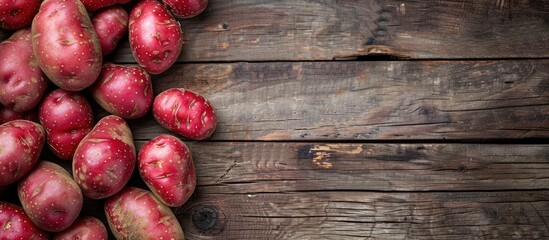 Poster - A top view of red skinned potatoes on a wooden surface with a duplicated image in the center, featuring copy space.