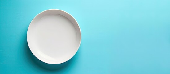 Leinwandbilder - Top view of an empty white plate on a blue background table with copy space image.