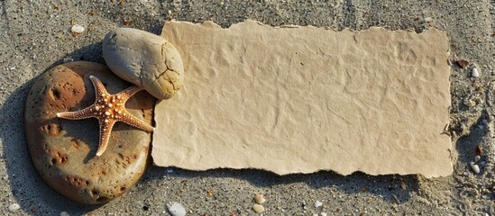 Aufkleber - A blank sheet of paper rests on sandy beach, next to a stone featuring a small seastar, creating a serene scene with copy space image.