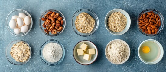 Wall Mural - Top view of baking ingredients for oat cookies with nuts and candied fruits on a blue surface, including bowls of flour, butter, eggs, oatmeal, sugar, nuts, providing copy space image.