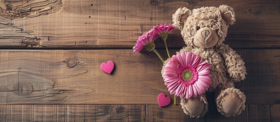 Poster - Valentine's Day love concept portrayed by a pink flower and teddy bear against a wooden background in a copy space image.