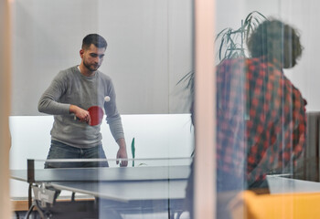 Wall Mural -  Business colleagues take a break from work to enjoy a game of table tennis, fostering teamwork and camaraderie in the workplace