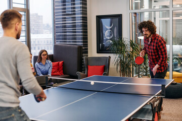 Wall Mural -  Business colleagues take a break from work to enjoy a game of table tennis, fostering teamwork and camaraderie in the workplace