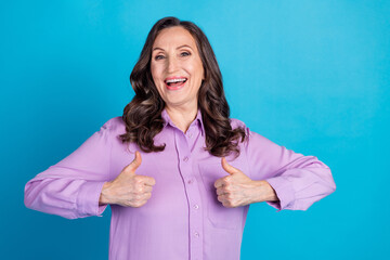 Photo of adorable lovely woman wear violet shirt showing two thumbs up empty space isolated blue color background