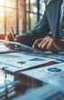 © yevgeniya131988 - Close up of hands using tablet, colleagues collaborating at desk with financial documents, graphs in office setting
