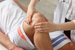 © New Africa - Sports injury. Doctor examining patient's knee in hospital, closeup