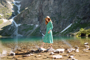 Woman tourist in summer dress enjoying beauty of nature looking at mountain lake. Concept of lifestyle, fashion, travel.