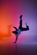 © LIGHTFIELD STUDIOS - A young African American man performs a dynamic dance move, silhouetted against a colorful gradient background.