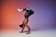 © LIGHTFIELD STUDIOS - A young African American man performs a handstand while dancing against a gradient backdrop of red and purple.