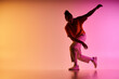 © LIGHTFIELD STUDIOS - A young African American man dances in front of a vibrant, colorful gradient background.
