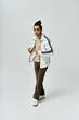 © LIGHTFIELD STUDIOS - A young African American man poses confidently in a stylish white jacket and brown pants, against a grey backdrop.