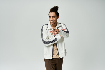 Wall Mural - A young African American man with a stylish haircut is wearing a white jacket and posing against a grey background.