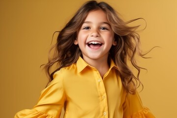 Wall Mural - Portrait of a cute smiling little girl in yellow shirt on yellow background