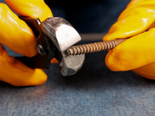 Close-up pliers and rusty screws in a person's hand
