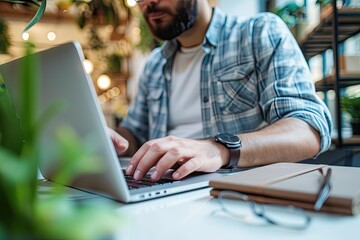 Leinwandbilder - a man sitting at a table with a laptop, Close-up of an entrepreneur working intensely on his laptop in a start-up environment