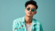© Arma - Handsome young man in a teal, floral-patterned shirt and sunglasses, posing confidently against a bright studio background. Perfect for summer fashion and lifestyle promotions. Copy space available.
