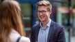 © Helen - A smiling man with glasses engages in a warm conversation outdoors, symbolizing friendliness, approachability, and positive human interaction in a casual setting.