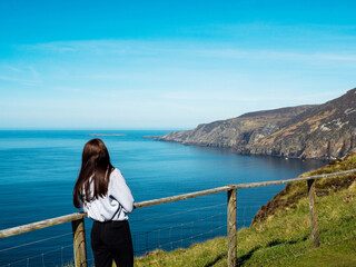 Wall Mural - Young teenager girl exploring beautiful Sliabh Liag, county Donegal, Ireland. Travel and tourism. Warm sunny day. Stunning Irish nature landscape scene in the background.