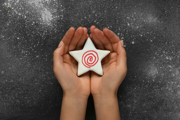 Sticker - Female hands with tasty Christmas cookie on grunge background, closeup