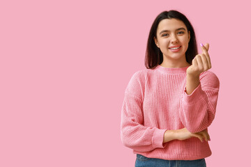 Sticker - Beautiful young girl showing heart gesture on pink background. Valentine's Day celebration