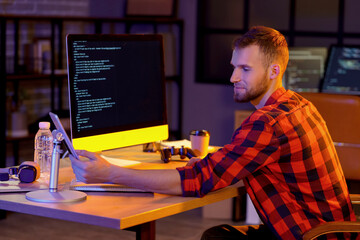 Poster - Young bearded programmer working with tablet computer in office at night