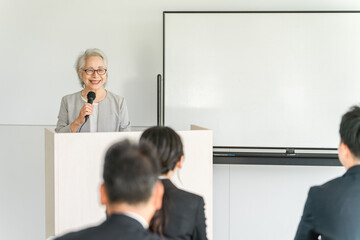 Canvas Print - 講演会・セミナー・講習会で講演・演説をする女性ビジネスウーマン（講師・先生・社長・代表）
