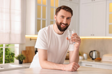 Sticker - Happy young man with glass of water in kitchen at morning