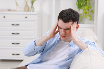 Canvas Print - Man suffering from headache on sofa at home