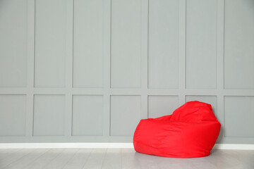 Wall Mural - Red bean bag chair near grey wall indoors. Space for text