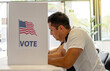 © Alan - Hispanic Person Voting in Election Booth. a young man focused on voting in an election booth during a United States election. elections, democracy, civic participation, and the voting process.