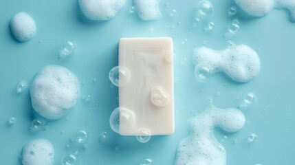 White soap bar and foam on pastel blue background. Bar of soap with bubbles. Flat lay, top view, copy space