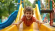 © Naknakhone - Happy preschooler boy playing on a slide on the playground in summer. copy space for text.