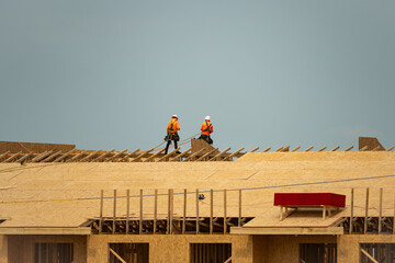 Roof repair on rooftop. Builder roofer install new roof. Construction worker roofing on a large roof apartment building development. Roofer carpenter working on roof structure construction site.