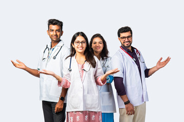 Group portrait of four indian asian young doctors in uniform standing against white background