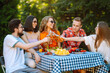 © maxbelchenko - Group of friends having backyard dinner party together. Young people enjoying leisure time together outside toasting with beer and barbecue. Vacation, picnic, weekend, nature.