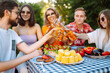 © maxbelchenko - Group of friends having backyard dinner party together. Young people enjoying leisure time together outside toasting with beer and barbecue. Vacation, picnic, weekend, nature.