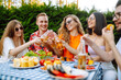 © maxbelchenko - Group of friends having backyard dinner party together. Young people enjoying leisure time together outside toasting with beer and barbecue. Vacation, picnic, weekend, nature.