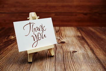 Poster - Thank You text on paper card on wooden background