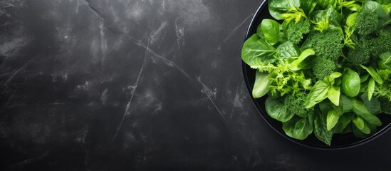 Aufkleber - Top view of salad leaves mixed in a black bowl on a dark slate, stone, or concrete surface, with ample copy space image.