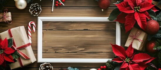 Poster - Festive holiday arrangement with a white frame, poinsettia, ornaments, gifts, and candy canes on a wooden backdrop, providing space for text or images in a top-down view. with copy space image