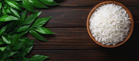 Aufkleber - Top-down perspective of Jasmine rice displayed on a dark wooden surface among lush green plants, featuring jasmine rice served in a wooden bowl with copy space image.