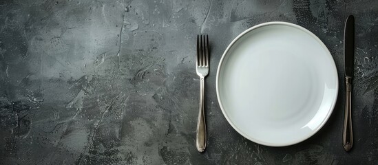 Poster - Gray stone concrete table with an empty white ceramic plate, knife, and fork. Perfect for menu or recipe concepts with copy space image.