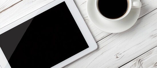 Aufkleber - Top view of a computer tablet with a black screen placed beside a cup of coffee on a white table, featuring a close-up shot and ample copy space image.