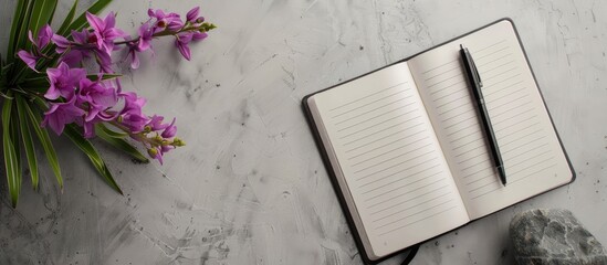 Leinwandbilder - Flat lay with a notebook, a pen, and a purple flower arranged on a gray backdrop, seen from a top view, creating a composition with copy space image.