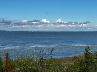 Scenic view of a calm sea with a clear blue sky and distant clouds